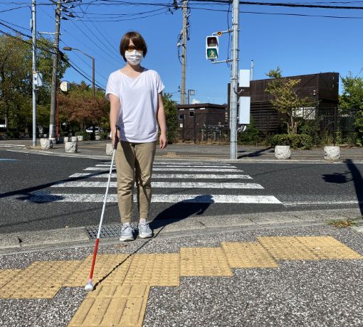 白杖を使用して横断歩道を歩く女性の写真